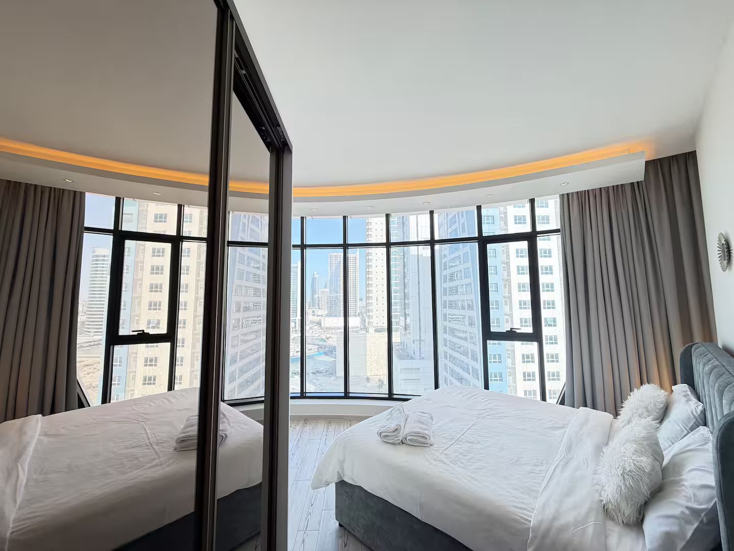 Habitación de hotel con dos camas, un espejo grande y vista a edificios altos.