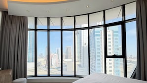 Una camera d'hotel con una finestra a volta, un letto, una sedia e vista sulla città.