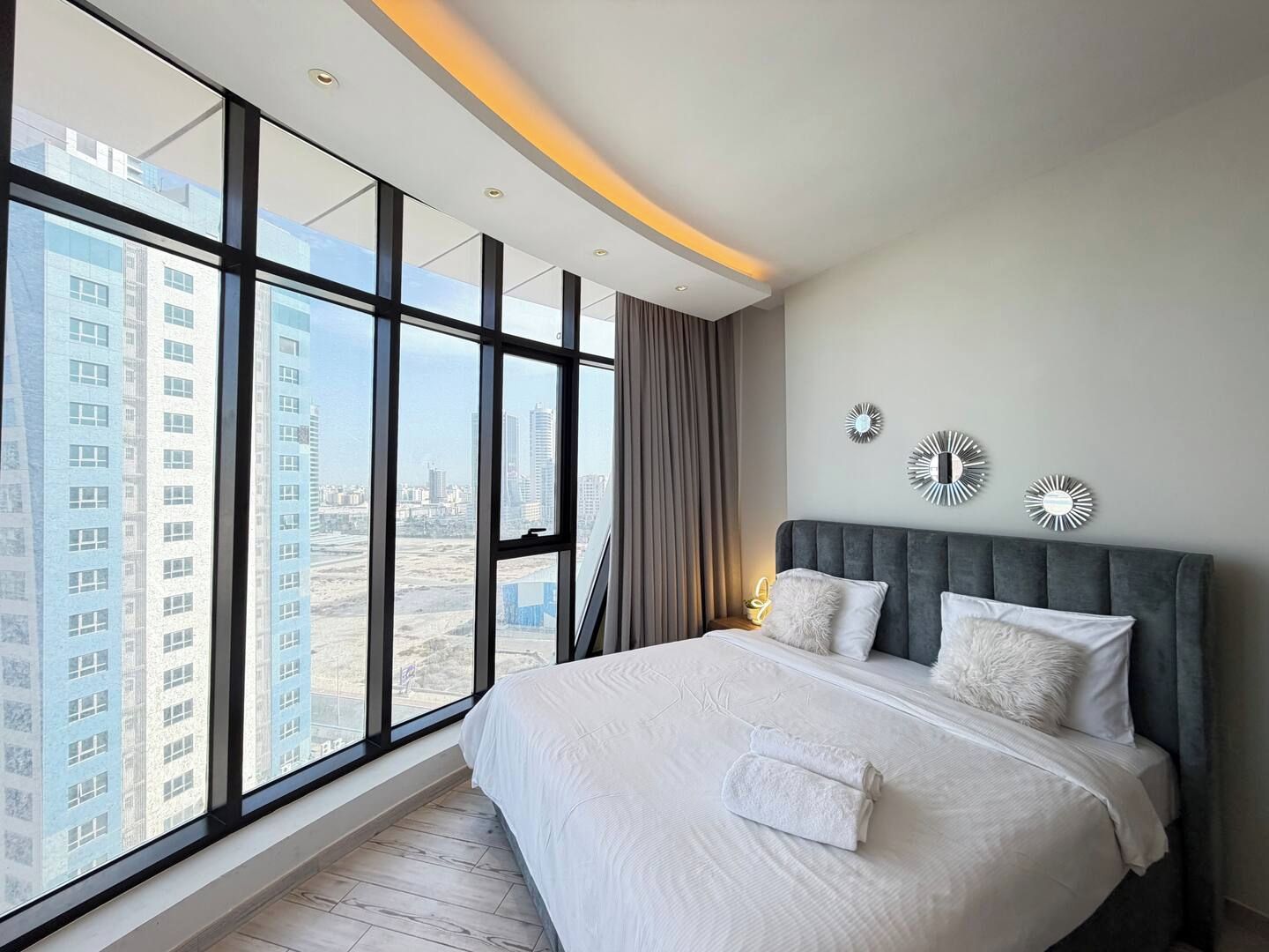 A modern bedroom with a large bed, city view, and decorative wall art.