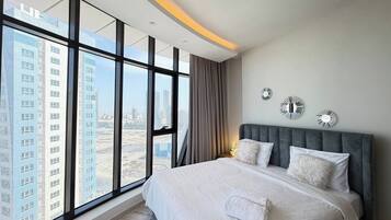 A modern bedroom with a large bed, city view, and decorative wall art.