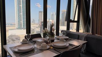 A dining table set for two with a view of a cityscape through large windows.