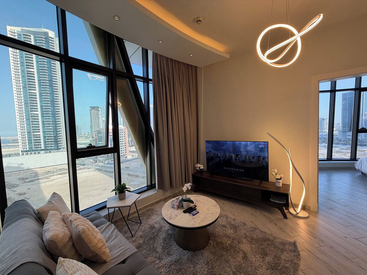 A modern living room with a large TV, a sofa, a coffee table, and a floor lamp.