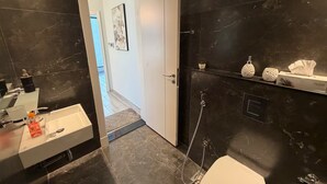 Un bagno moderno con un WC bianco, un lavandino con uno specchio e una zona doccia.