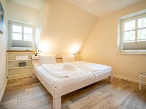 Ein Schlafzimmer mit einem Bett, einem Nachttisch, einem Regal und einem Fenster.