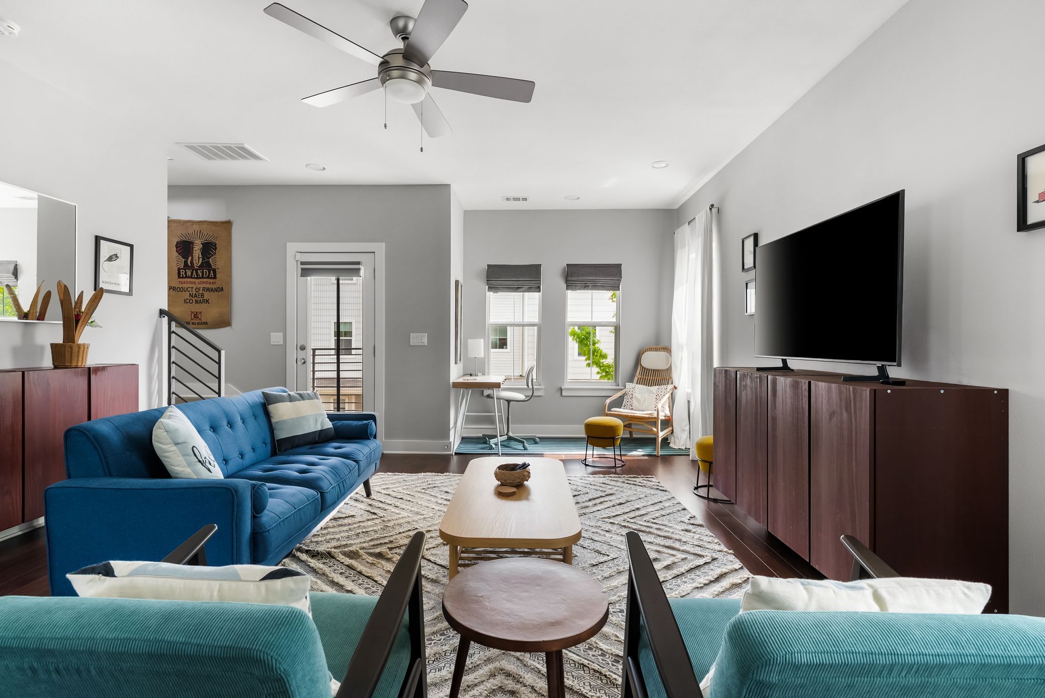 A living room with a blue sofa, a coffee table, a TV, and a ceiling fan.