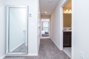 A hallway leading to a bedroom with a door, a bathroom with a sink and lights, and a carpeted floor. - 3BR Townhome in Fiesta Key Near Disney Parks (Kissimmee)