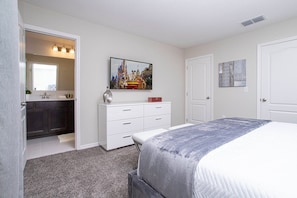 A bedroom with a bed, a dresser, a mirror, and a painting. - 3BR Townhome in Fiesta Key Near Disney Parks (Kissimmee)