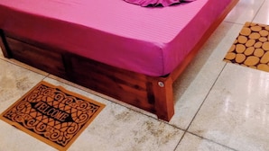A bed with a purple bedspread and pillows, a welcome mat, and a wooden headboard. - Guest House - Habarana (Habarana)
