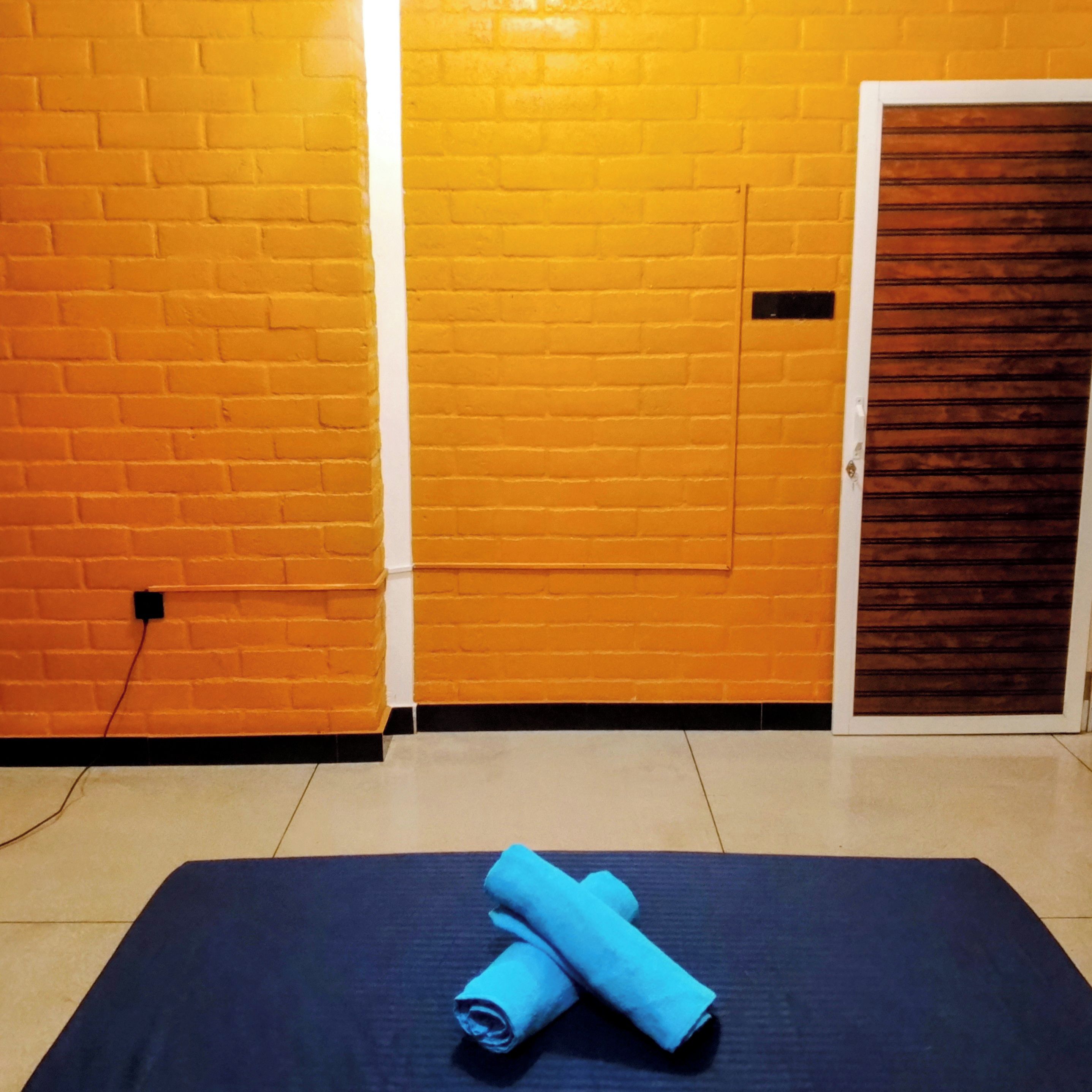 Une pièce avec un mur en briques, une porte en bois et un tapis bleu sur le sol.