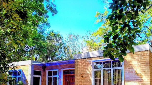 A two-story building with a brick facade, a front entrance with a door, and a window with vertical blinds. - Guest House - Habarana (Habarana)