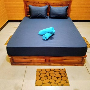 Ein Bett mit dunkelblauer Matratze und Kissen, ein Holz-Kopfteil und ein gemustertes Teppich auf dem Boden.