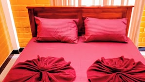 A bed with a red bedspread and two pillows. - Guest House - Habarana (Habarana)