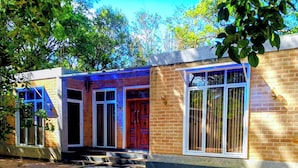 A two-story building with a brick facade, large windows with metal bars, and a front entrance with a wooden door. - Guest House - Habarana (Habarana)