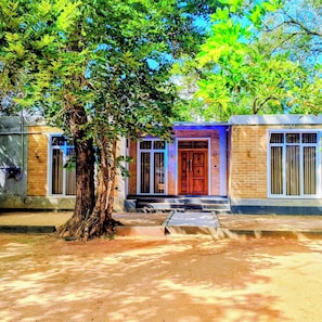 A building with a central entrance, a tree in front, and a clear sky.