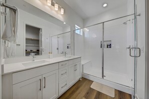 Un bagno moderno con box doccia in vetro, uno specchio grande e un mobile lavabo.