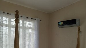 En seng med himmelseng, en træsenggavl, et natbord med lampe og en stol med et håndklæde.