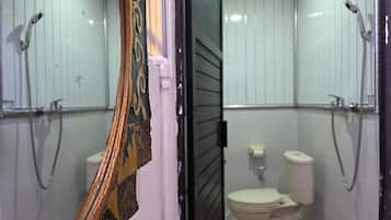 Un baño con paredes de azulejos blancos, un inodoro y dos cabezales de ducha.