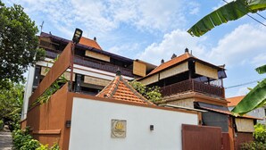 Una villa con fachada blanca, un portón de entrada marrón y techo de tejas.