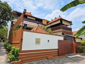 A villa with a white facade, a brown entrance gate, and a tiled roof. - Dahlia Moon Saba Beach (Bali)