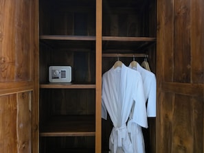 A wooden wardrobe with a built-in radio and white robes hanging on a rack.