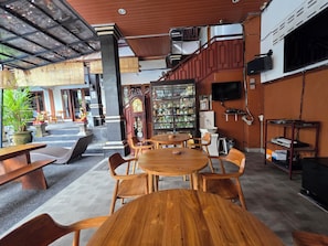 A restaurant with wooden tables and chairs, a clock, and a shelf with various items.