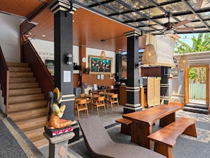 A spacious indoor area with a wooden staircase, a dining area with tables and chairs, and a statue.