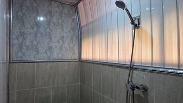 Baño con ducha, inodoro y paredes con azulejos.
