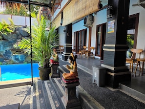 A poolside area with a stone pathway, potted plants, and outdoor seating.