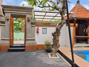 A building entrance with a wooden door, a fire extinguisher, and a small pool area.