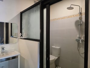 A bathroom with a shower, toilet, sink, and a mirror. - Dahlia Moon Saba Beach (Bali)