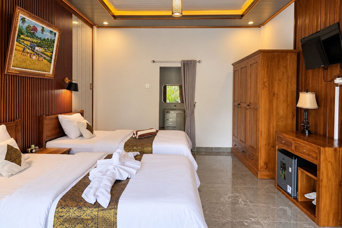 A hotel room with two beds, a television, a cabinet, and a painting on the wall.