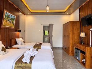 A hotel room with two beds, a television, a cabinet, and a painting on the wall. - Dahlia Moon Saba Beach (Bali)