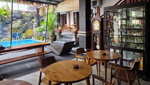 Un restaurante con terraza, piscina y una exhibición de diversos objetos.