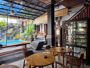 A restaurant with outdoor seating, a pool, and a display of various items. - Dahlia Moon Saba Beach (Bali)