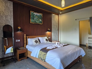 A hotel room with a wooden bed, a nightstand, a mirror, and a wall-mounted painting.
