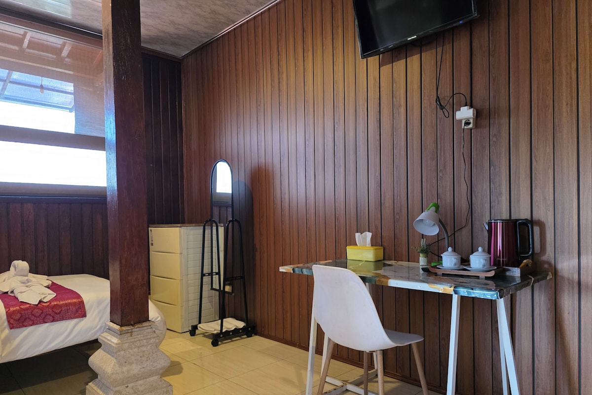 A hotel room with a bed, a desk with a chair, a television, and a window.