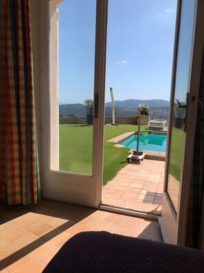 Ein Zimmer mit einer Schiebeglastür, die zu einem Poolbereich mit Bergblick führt.