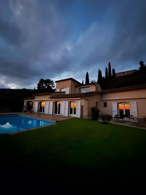 Ein Haus mit Swimmingpool, Terrasse und Blick auf den Sonnenuntergang.