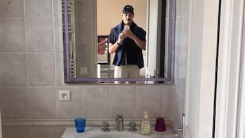 A bathroom with a white sink, a mirror, and a trash bin.