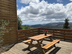 A wooden deck with a picnic table and benches, overlooking a mountainous landscape. - Room 'Chambre N°3' with Sea and Estérel Mountain View, Pool, Wi-Fi, Air Conditioning and Parking (Cabris)