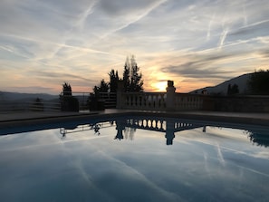 Klarer Himmel bei Sonnenuntergang, ein Pool, der die Umgebung spiegelt, und eine Aussicht auf ferne Berge.