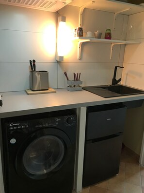 A compact kitchen with a washing machine, a sink, and a countertop with various utensils. - Room 'Chambre N°3' with Sea and Estérel Mountain View, Pool, Wi-Fi, Air Conditioning and Parking (Cabris)