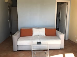 Ein Wohnzimmer mit einer Couch, einem Couchtisch und einer Tür zu einem weiteren Raum.