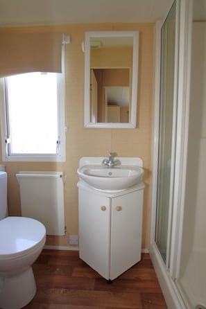 Un baño pequeño con inodoro, lavabo y espejo.