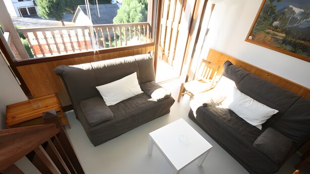 Een woonkamer met twee donkergrijze banken, een witte salontafel en een houten stoel.