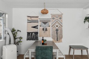 Ein Essbereich mit Tisch, Stühlen und Wandkunst aus Makramee.