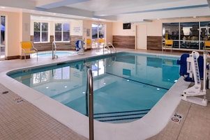 An indoor swimming pool with clear water, a lifeguard chair, and a sign indicating a maximum load of 6.