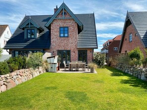 Ein Wohnhaus mit Backsteinfassade, geneigtem Dach und einem gepflegten Rasen.