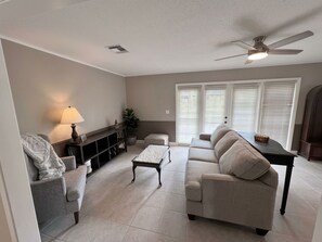 A living room with a sofa, a coffee table, a lamp, and a ceiling fan.