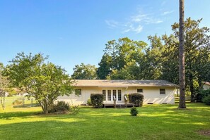 A single-story house with a front porch, surrounded by a well-maintained lawn and trees.